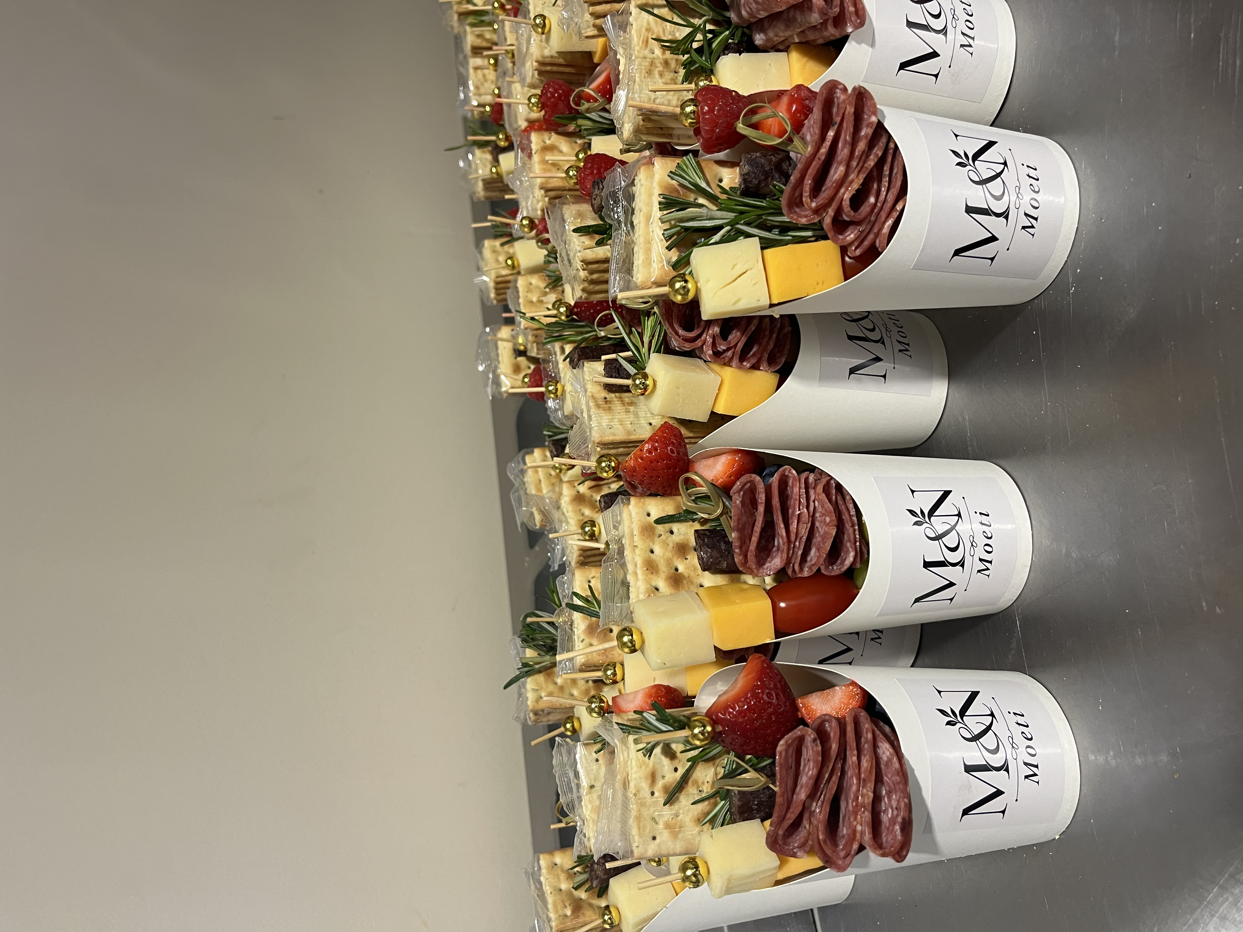 Row of freshly styled Nibble & Nest charcuterie cups with cured salami, cheeses, crackers and fruit