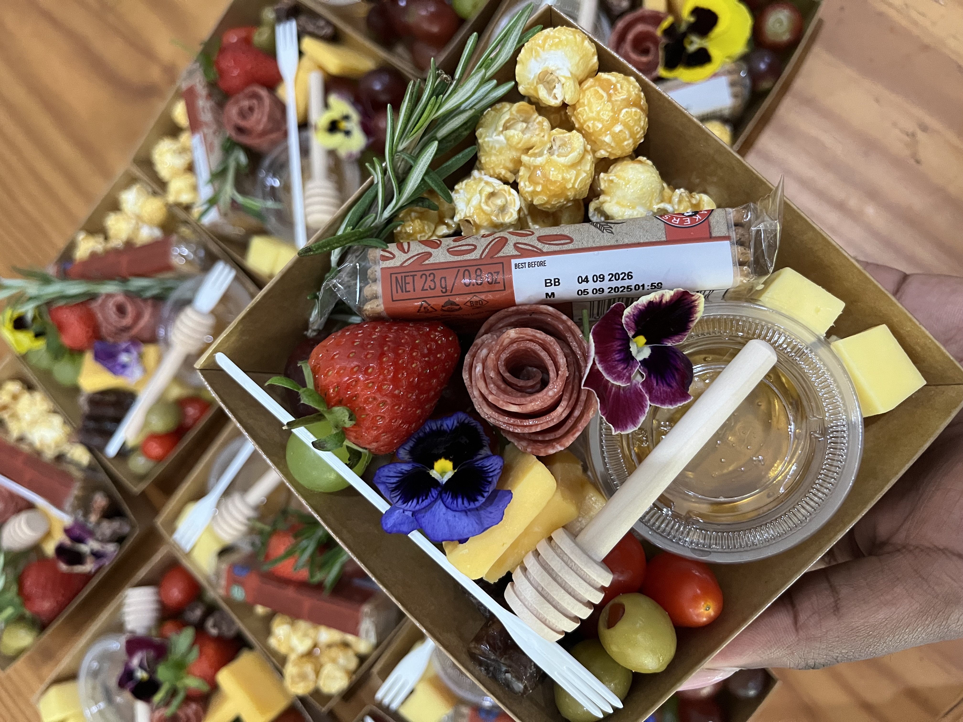 A charcuterie box held open showing the grazing contents