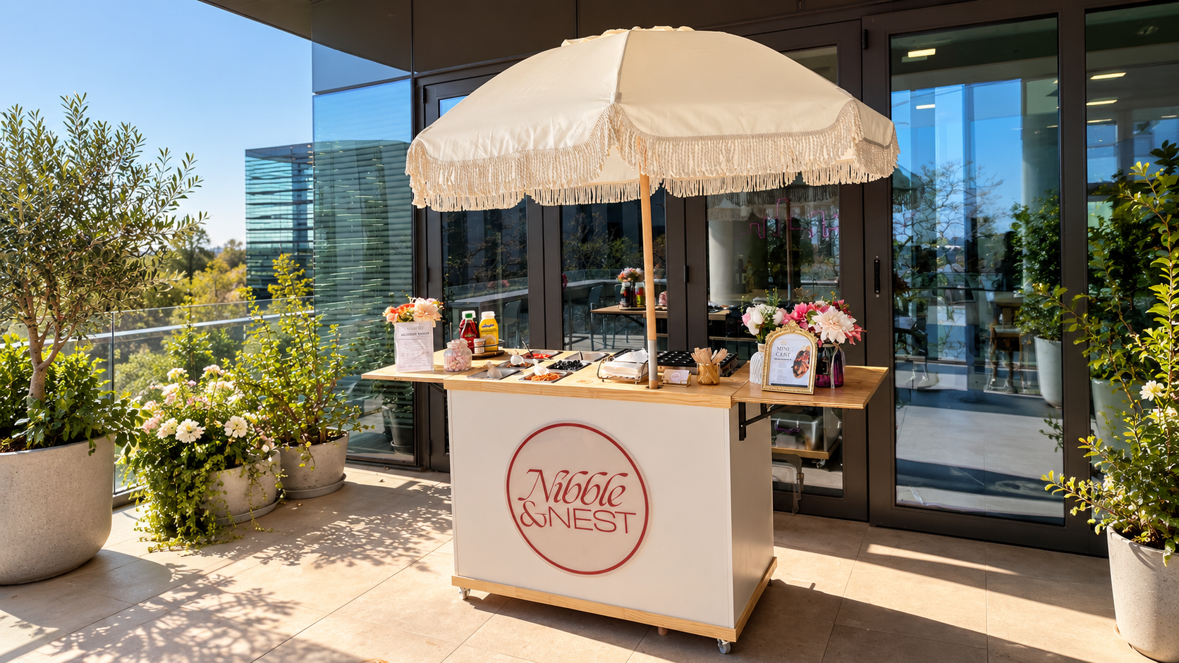 Nibble & Nest mini pancake cart setup on a sunny terrace with fringed parasol and toppings