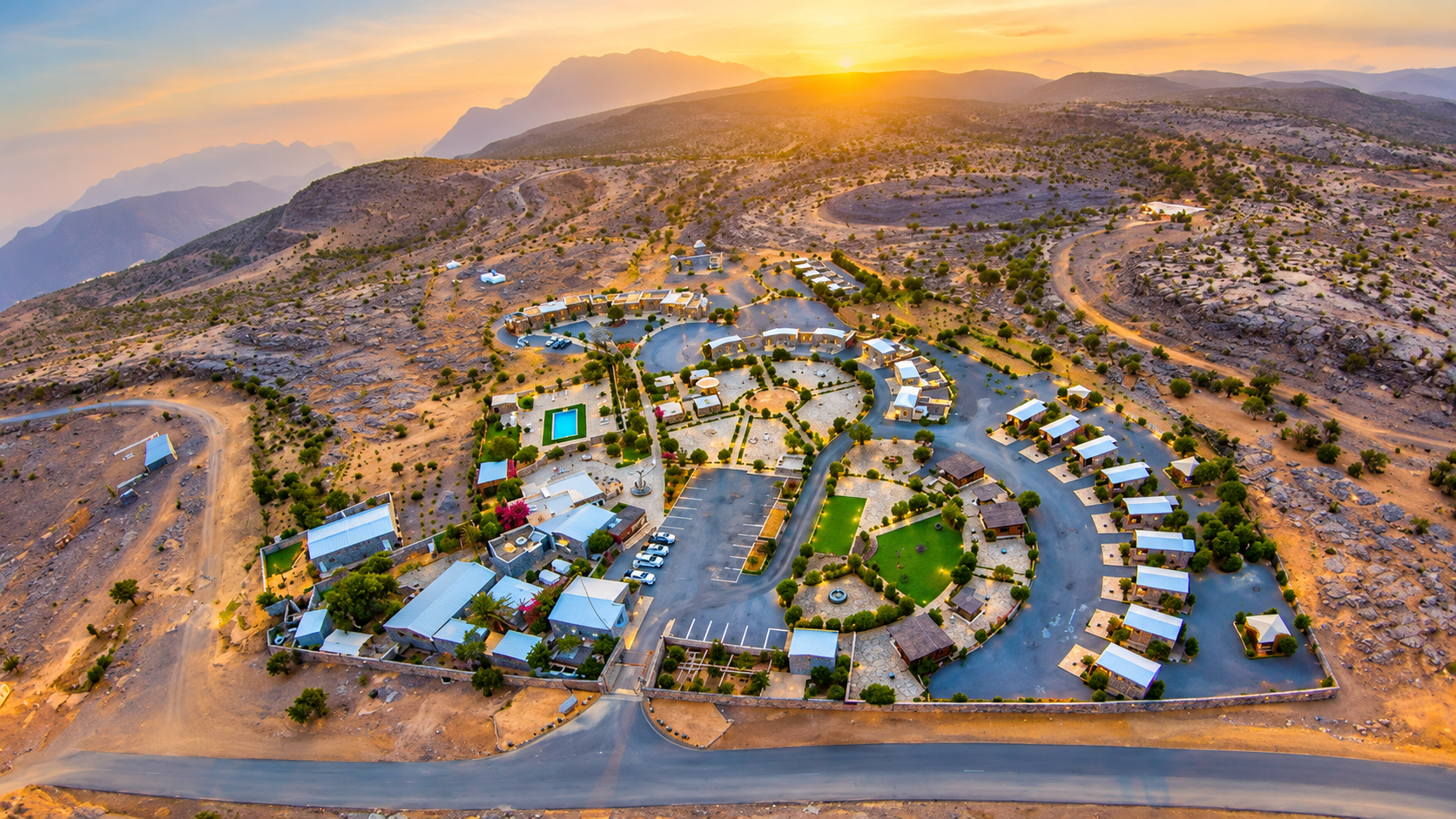 Aerial sunset panorama of Jebel Shams Resort and mountain chalets