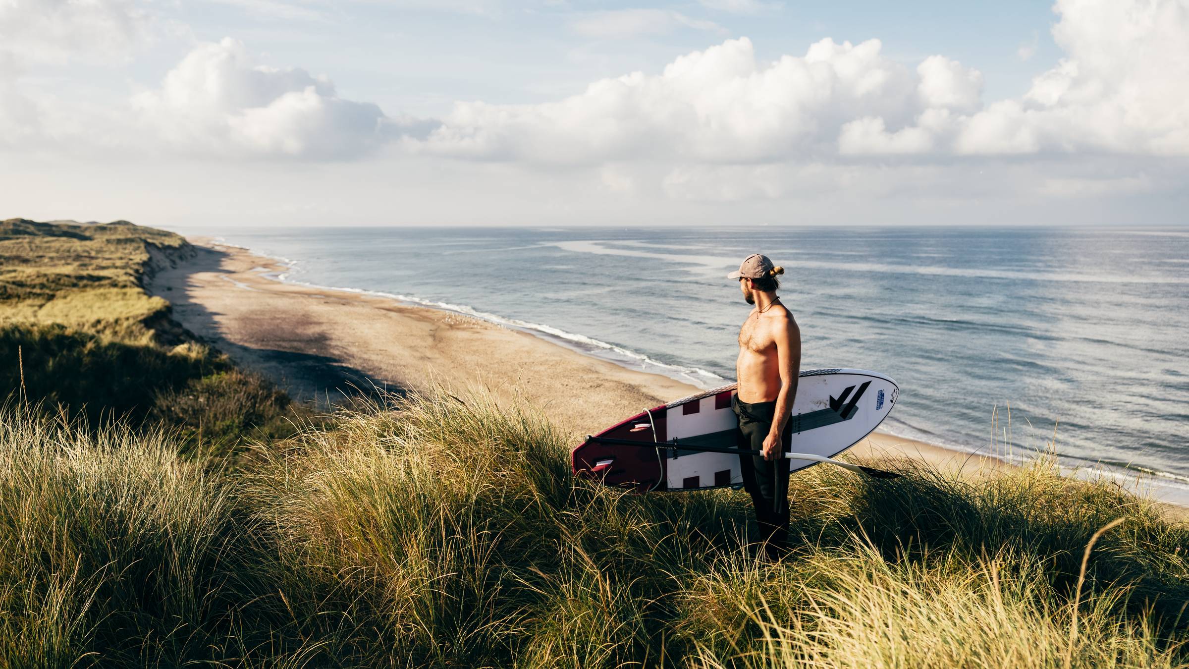 Surfer mit Board in den Dünen mit Blick aufs Meer, Oliver Farys