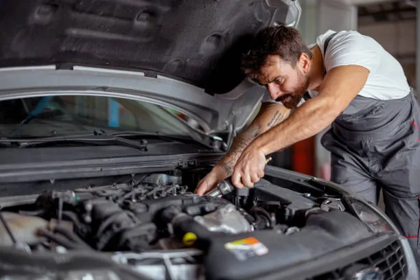 Mechanic performing engine repair under the hood of a vehicle