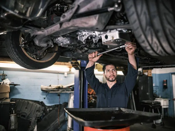 Auto technician performing underbody service on a vehicle lift