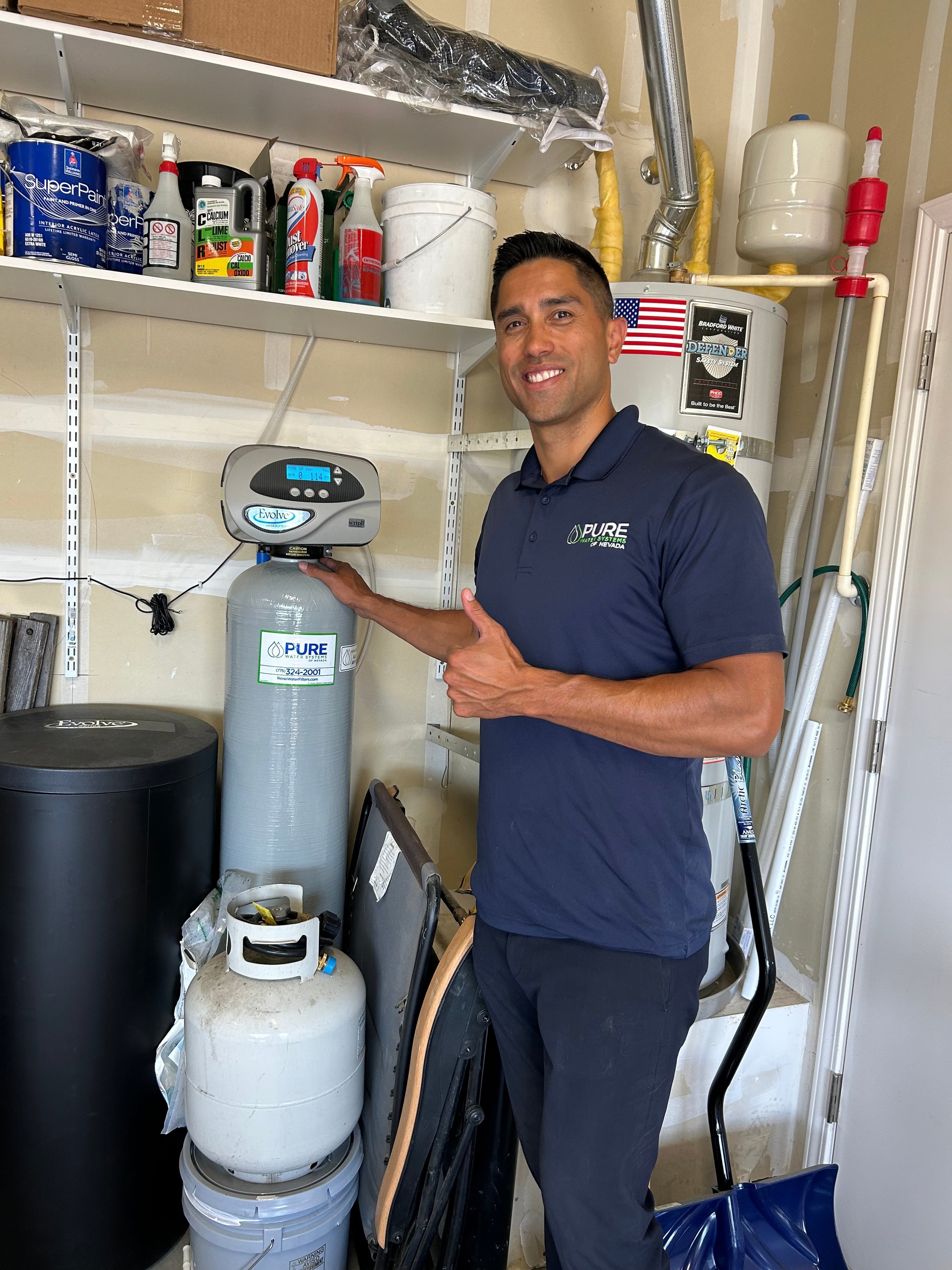 Kawika Burdine giving a thumbs-up next to an installed water softener system