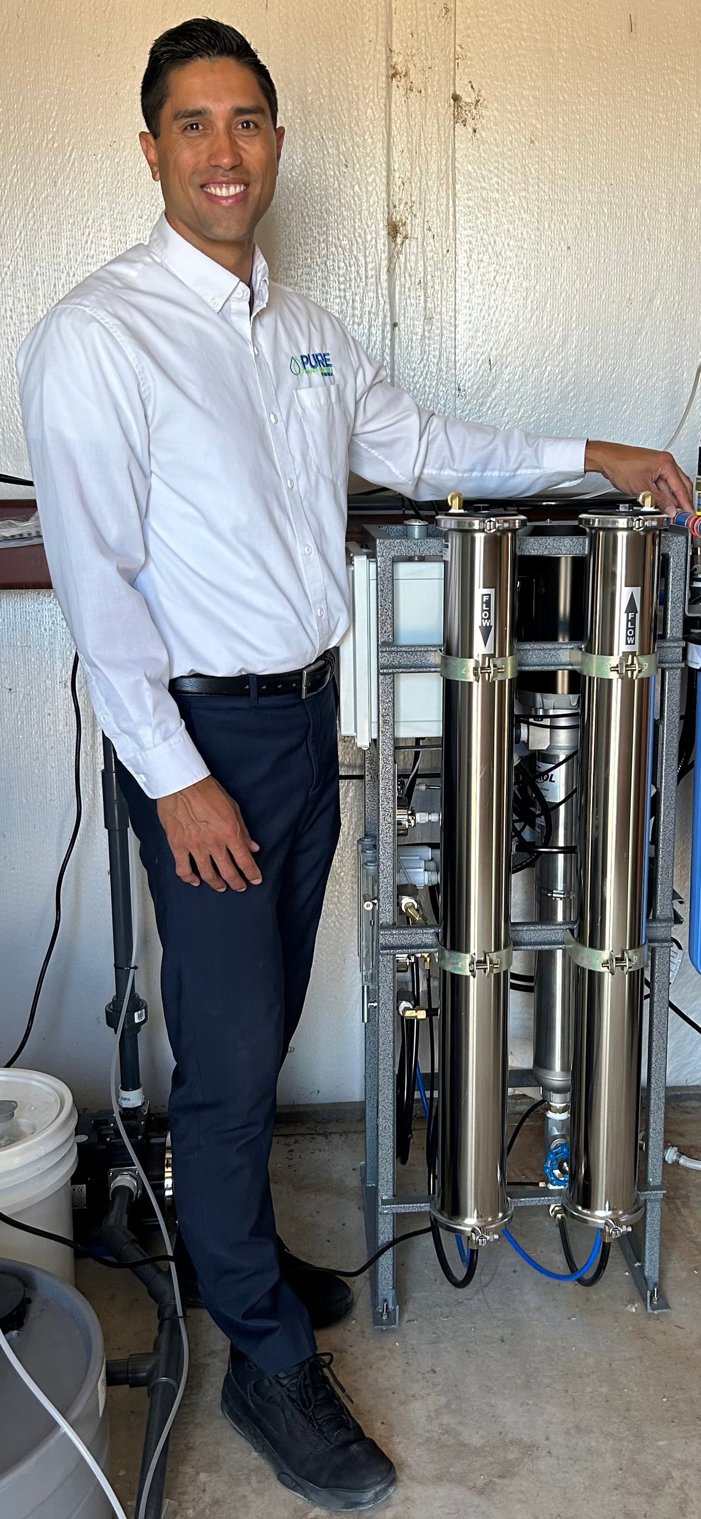 Kawika Burdine beside an installed stainless-steel filtration system