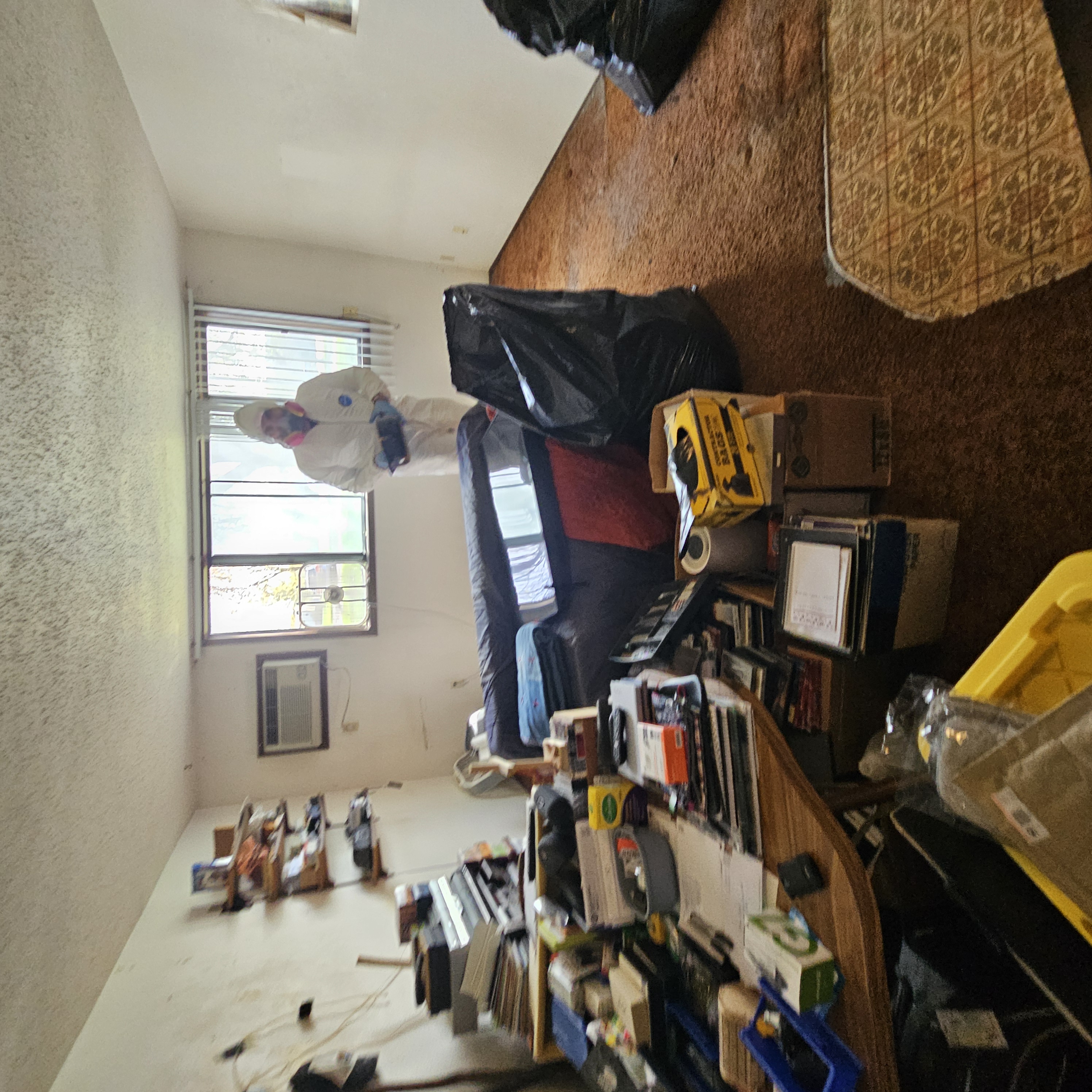 Painless Path crew member in protective suit and respirator bagging up debris during an apartment cleanout