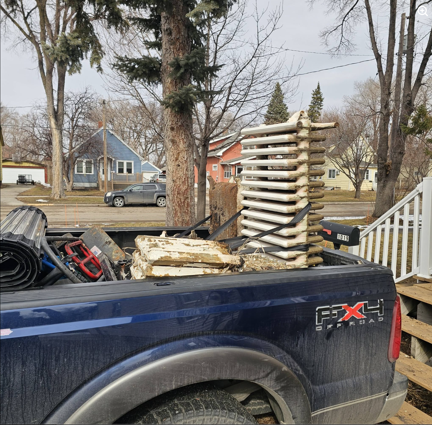 Heavy cast iron radiators loaded and strapped into truck bed for removal and recycling by Painless Path Movers