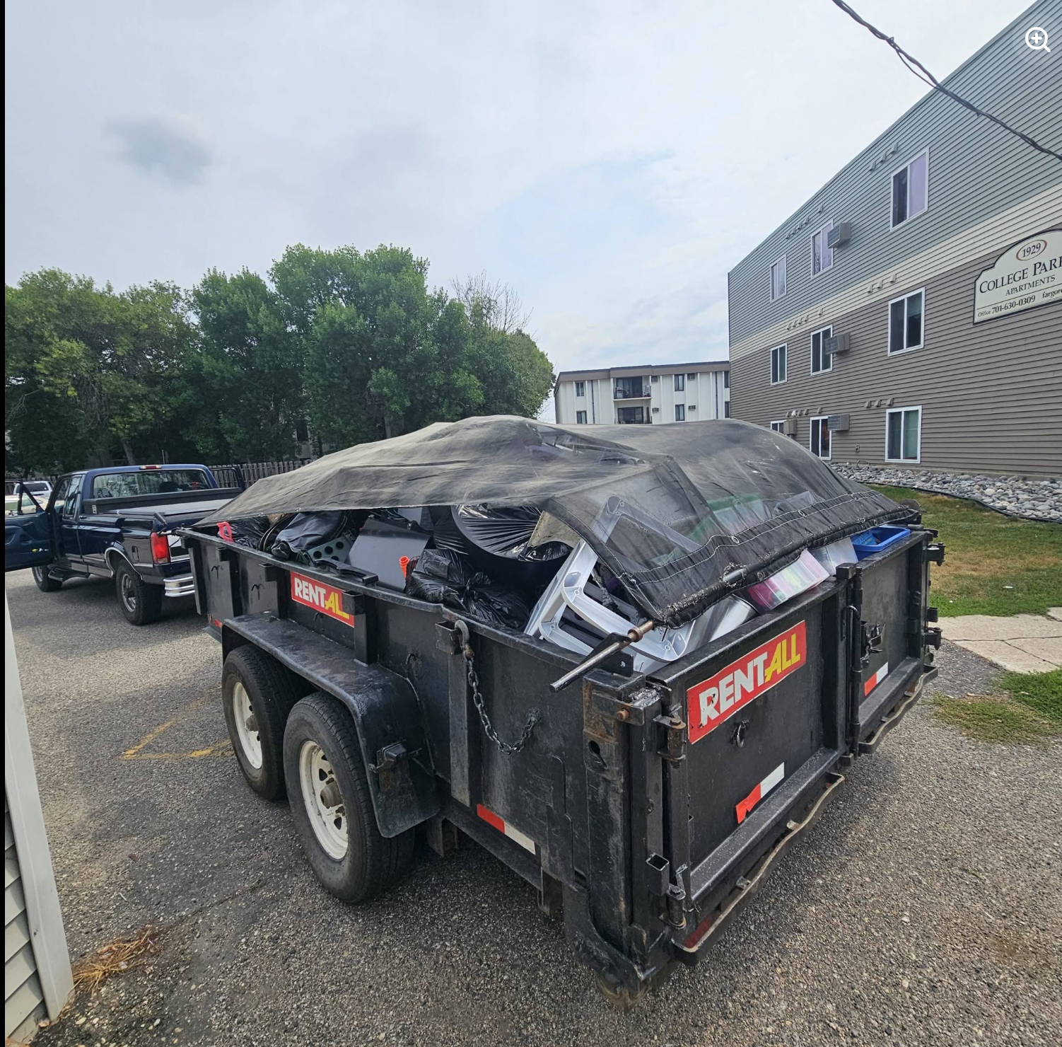 Painless Path Movers high-capacity dump trailer fully loaded and tarped for apartment tenant cleanout at College Park Apartments