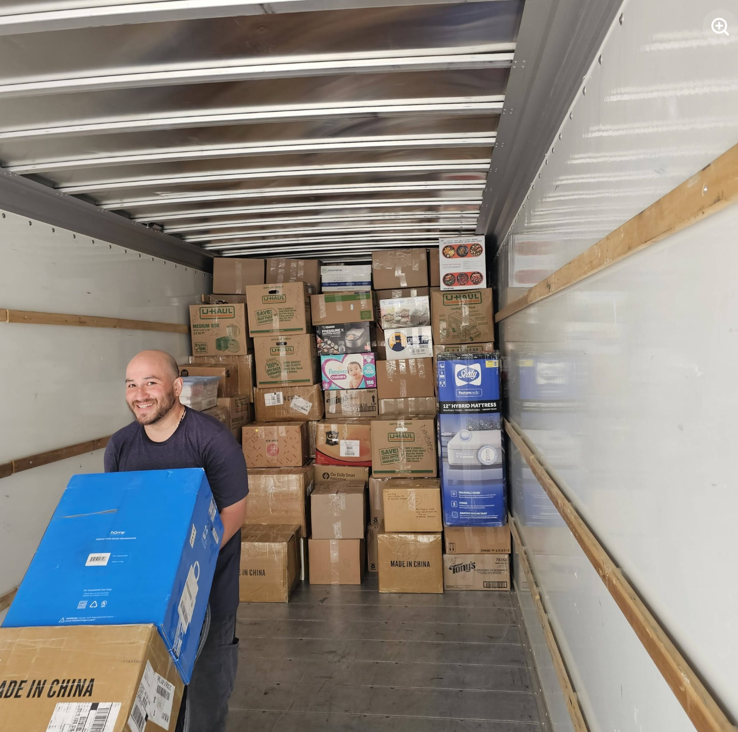 Painless Path Movers crew member smiling beside stacked moving boxes loaded in a truck