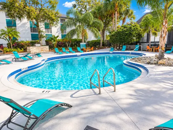 Commercial hotel and resort swimming pool complex with lounge chairs and palm trees