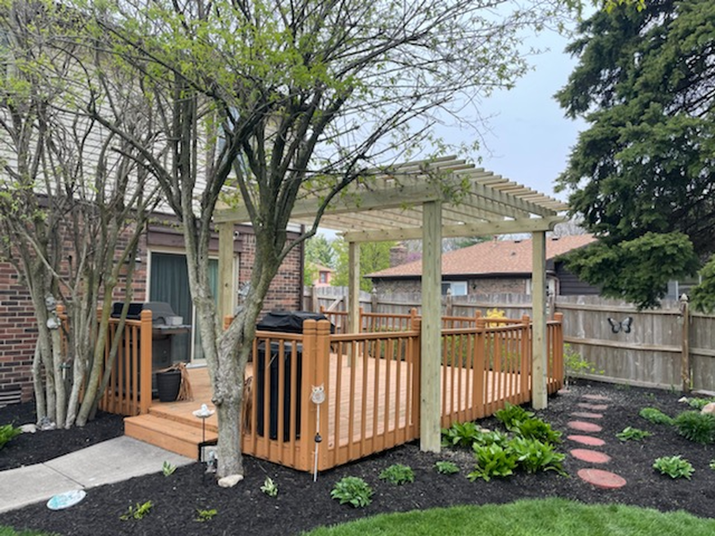 Custom wooden pergola built over a raised backyard deck with railings