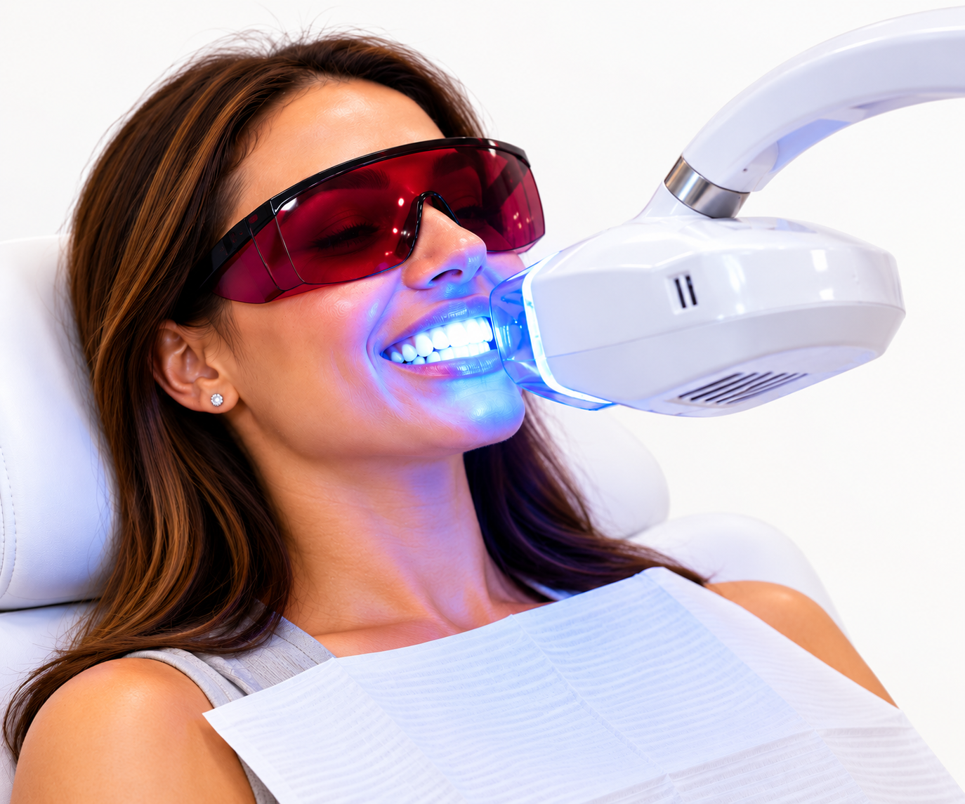 Woman receiving professional LED teeth whitening treatment with red protective eyewear