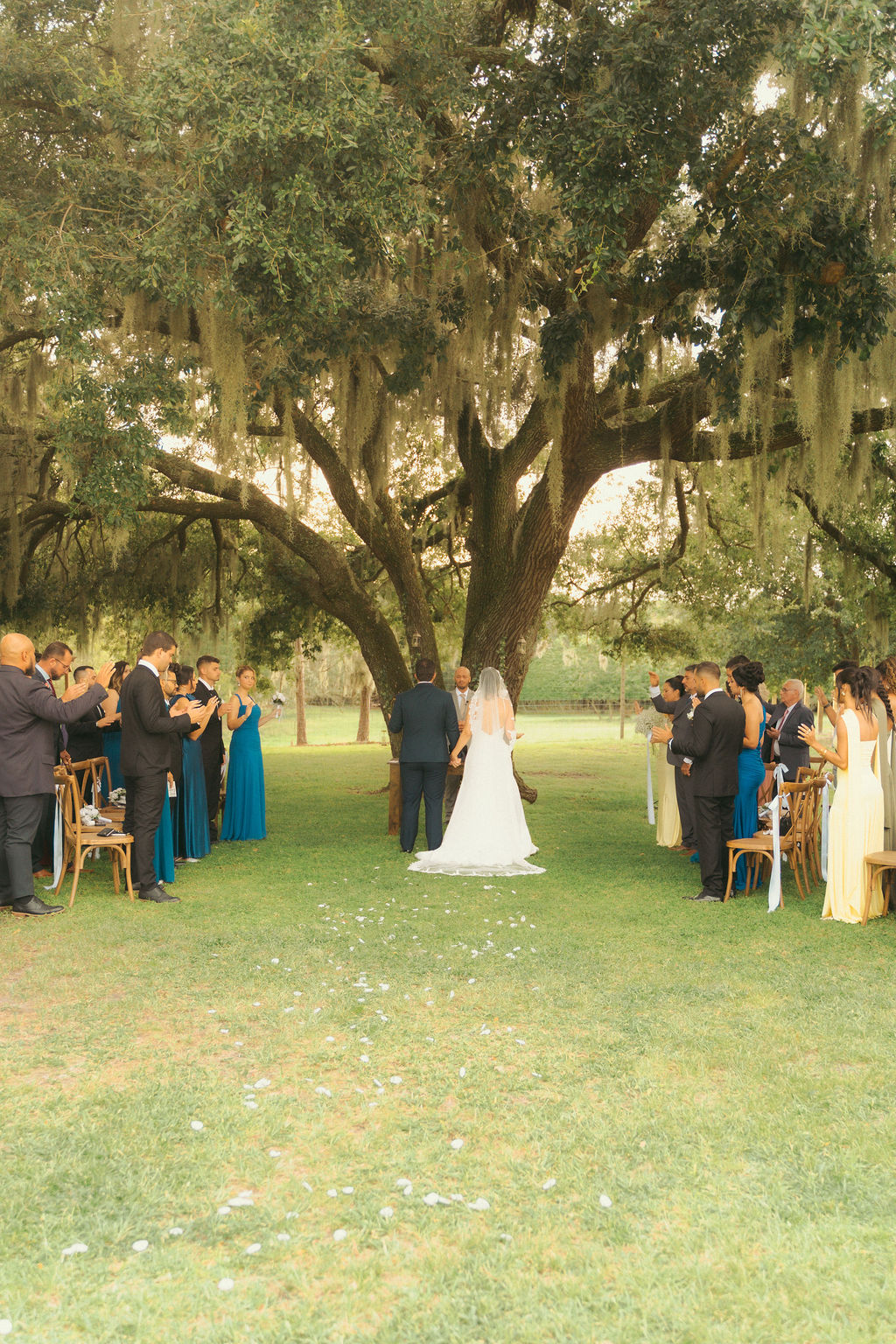 Outdoor wedding ceremony beneath the oaks at Cespedes Ranch with bride, groom, wedding party, and guests