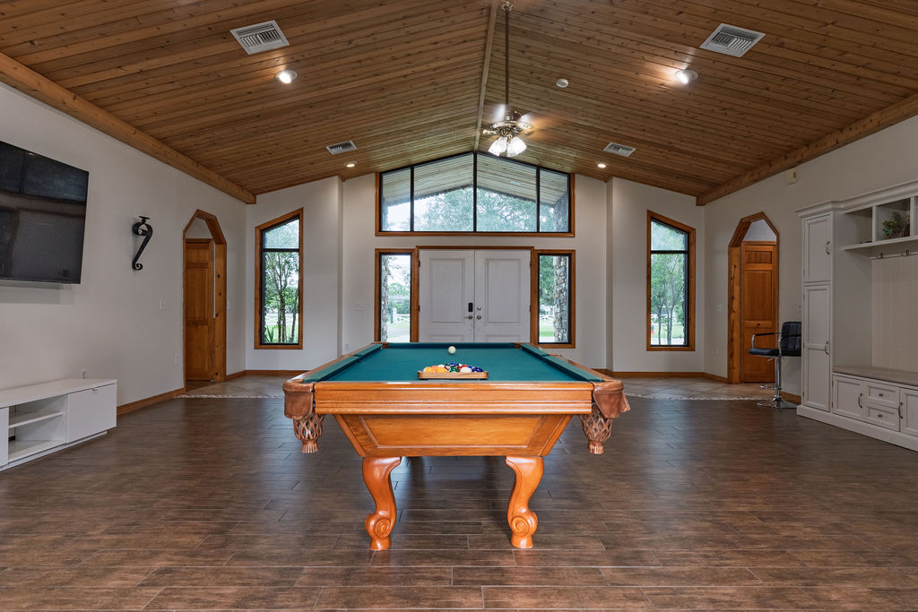 Ranch-house great room with custom billiard table, vaulted wood ceiling, and entertainment cabinetry at Cespedes Ranch