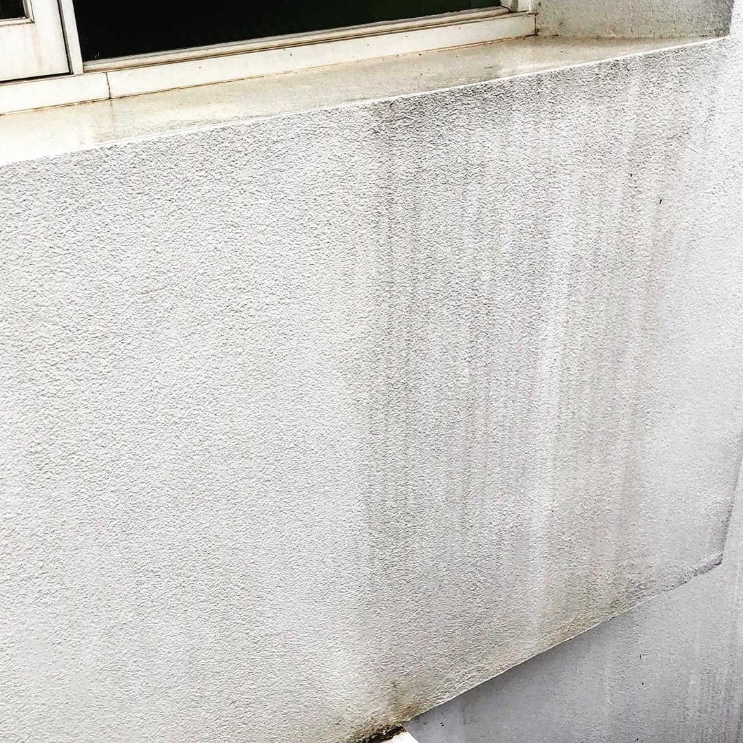 Close-up of rendered wall showing dark run-off stains treated with soft wash cleaning
