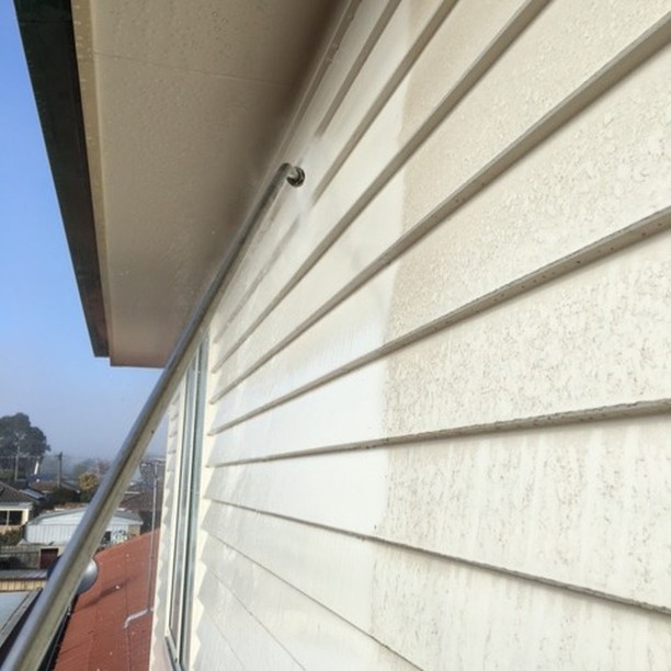 Soft washing wand cleaning painted weatherboards showing clean contrast