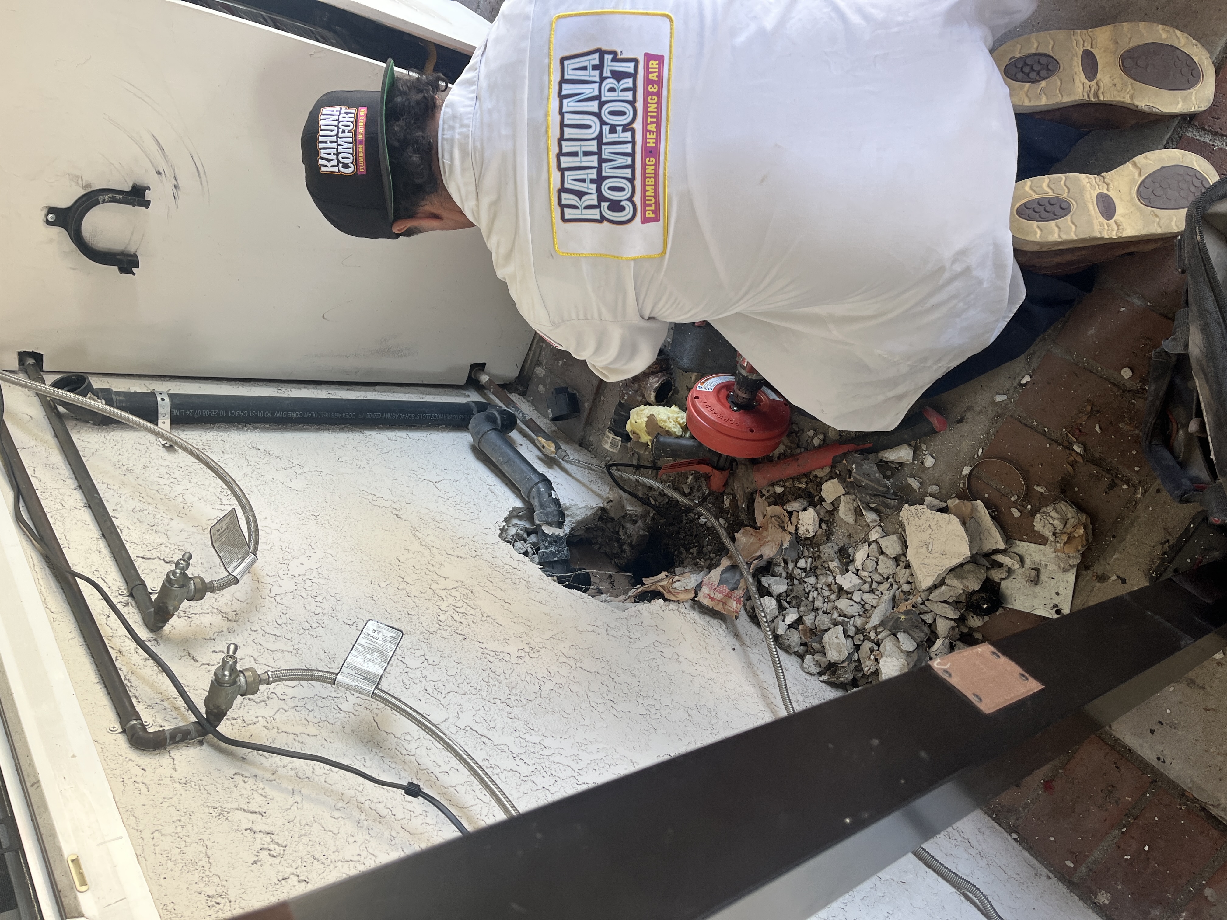 Plomero con uniforme oficial de Kahuna Comfort trabajando en la reparación de tuberías en Orange County