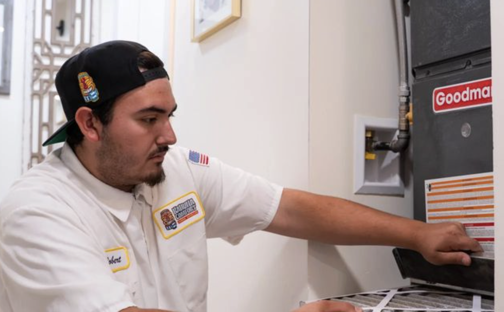 Técnico oficial de Kahuna Comfort con uniforme y gorra de la marca realizando servicio al sistema