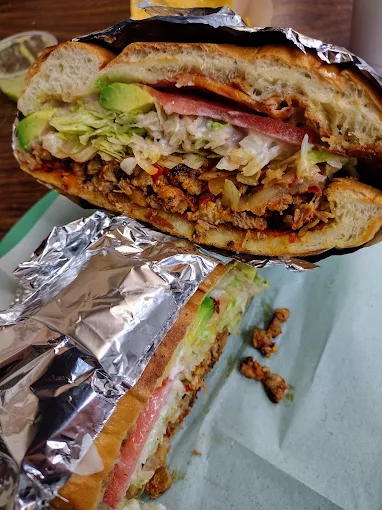 Hearty Mexican torta sandwich packed with grilled meats, fresh avocado, lettuce, and warm toasted bolillo bread