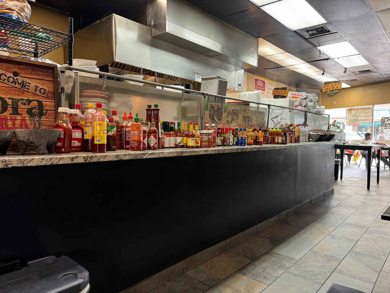 Taqueria Sonora order counter featuring extensive hot sauce collection and open kitchen