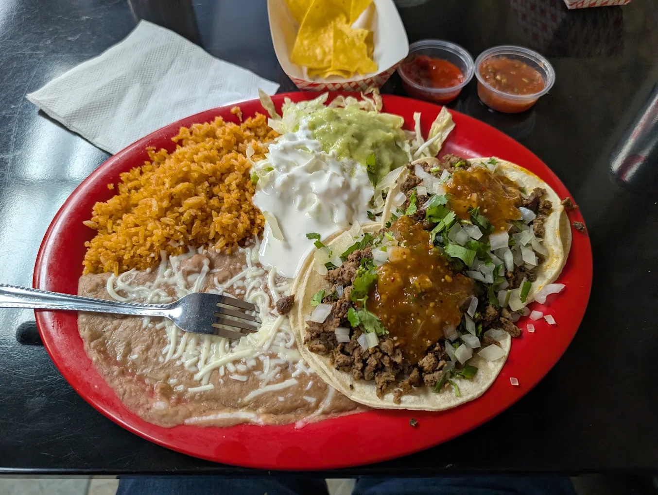 Authentic Mexican taco plate combo with Mexican rice, refried beans, guacamole, and sour cream