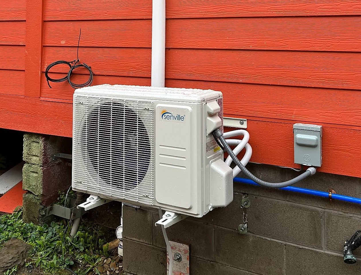 Ductless mini-split outdoor unit mounted on the side of a home