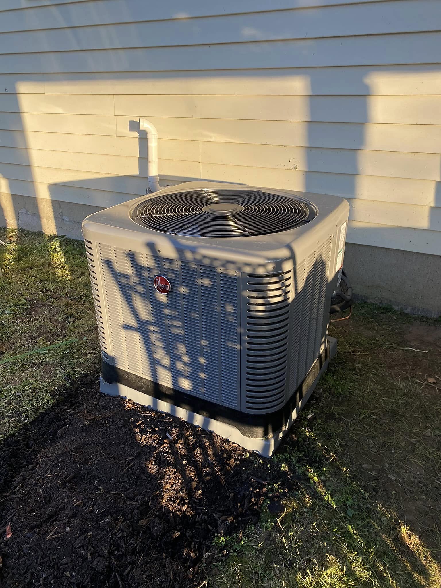 Outdoor central air conditioning condenser unit installed on a pad outside a home