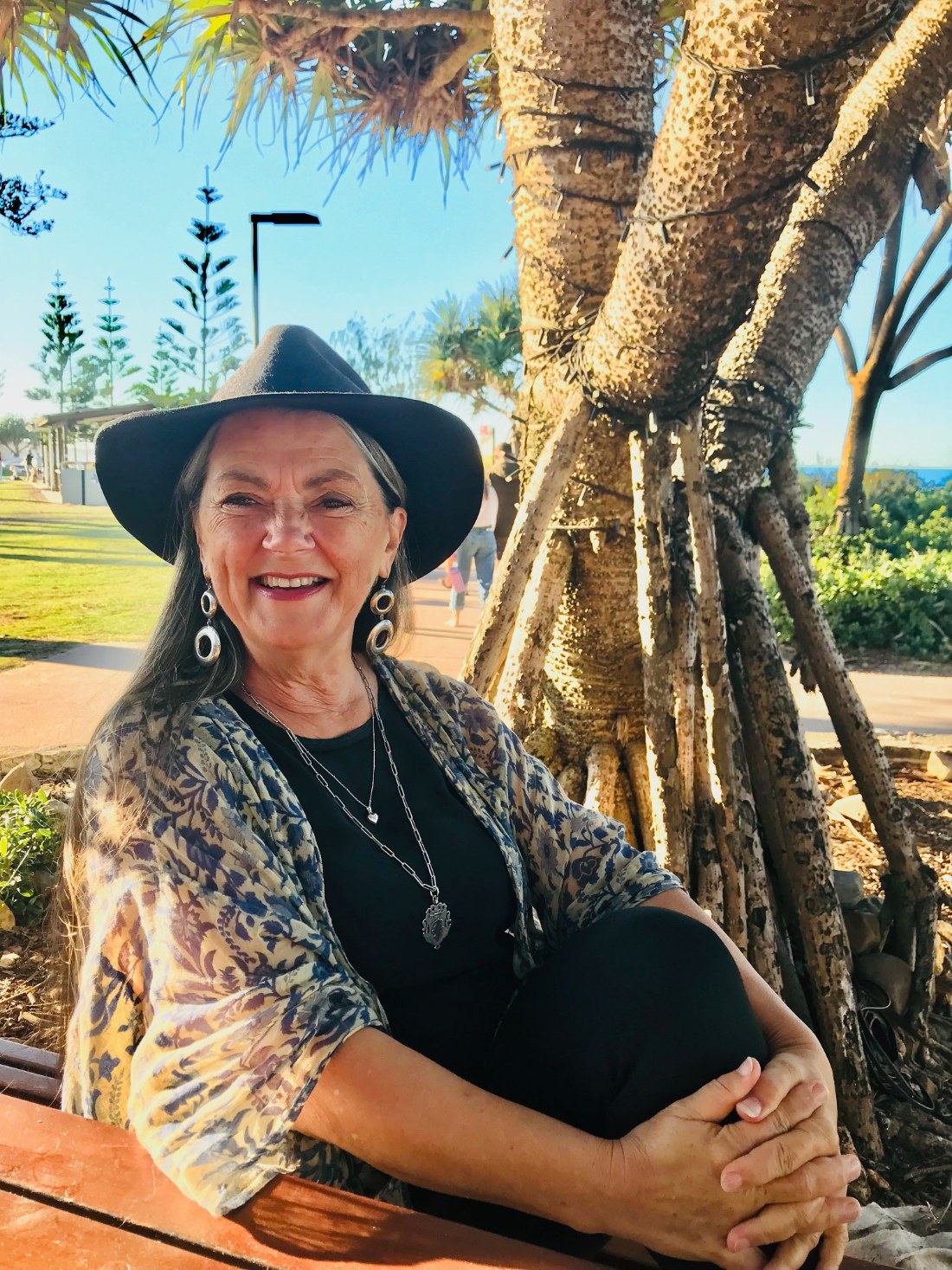 Shari Elle smiling in black hat and printed shawl