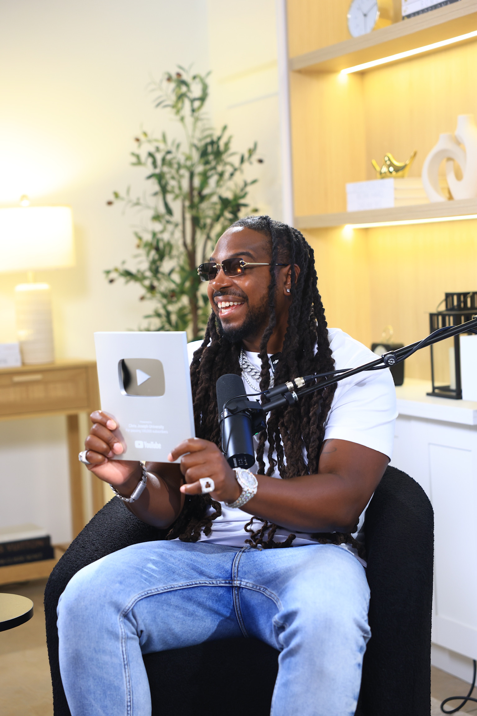 Chris Joseph holding YouTube 100K award plaque in studio