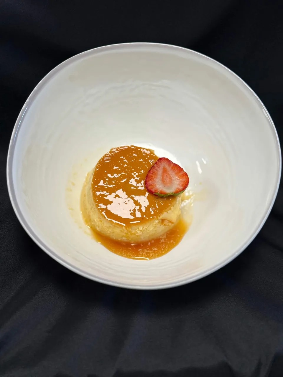 Artisanal Caramel Flan Plated in White Ceramic Bowl with Fresh Strawberry
