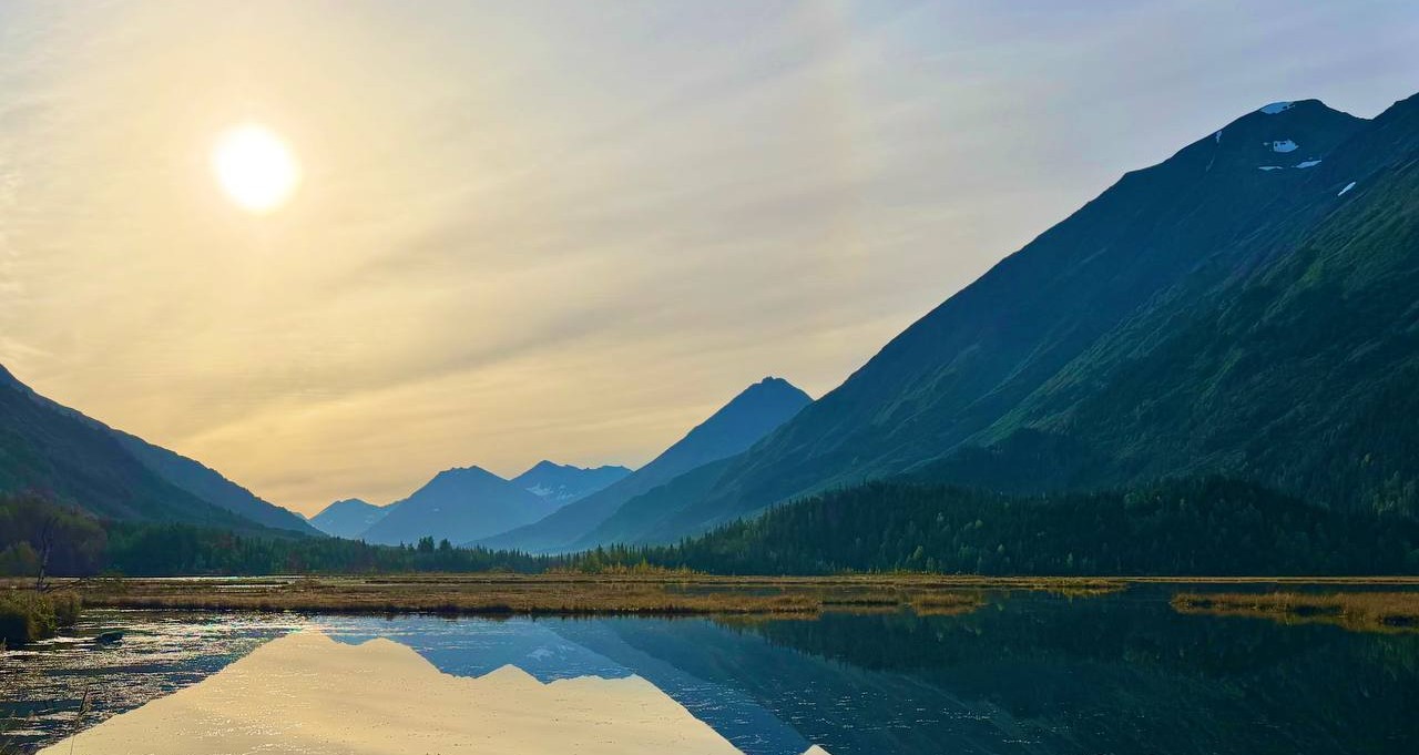 Majestic mountain lake with glassy water reflections at golden sunrise