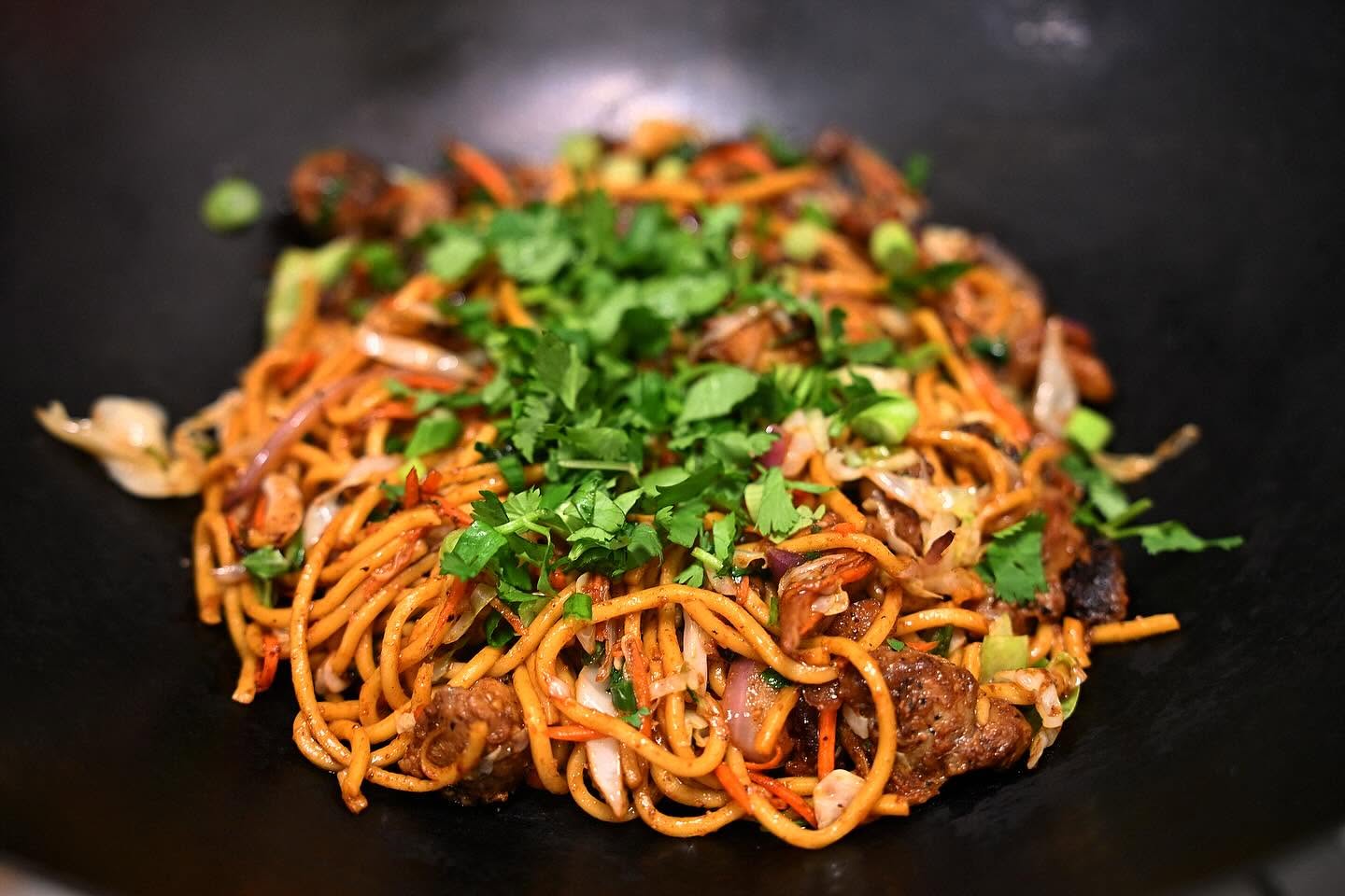 Wok-tossed noodles with fresh cilantro and savory vegetables at Nori in Omaha
