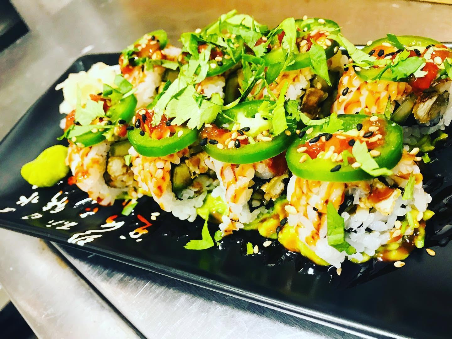 Specialty sushi roll topped with fresh jalapeño rounds, cilantro, sesame seeds, and house sauce at Nori in Omaha
