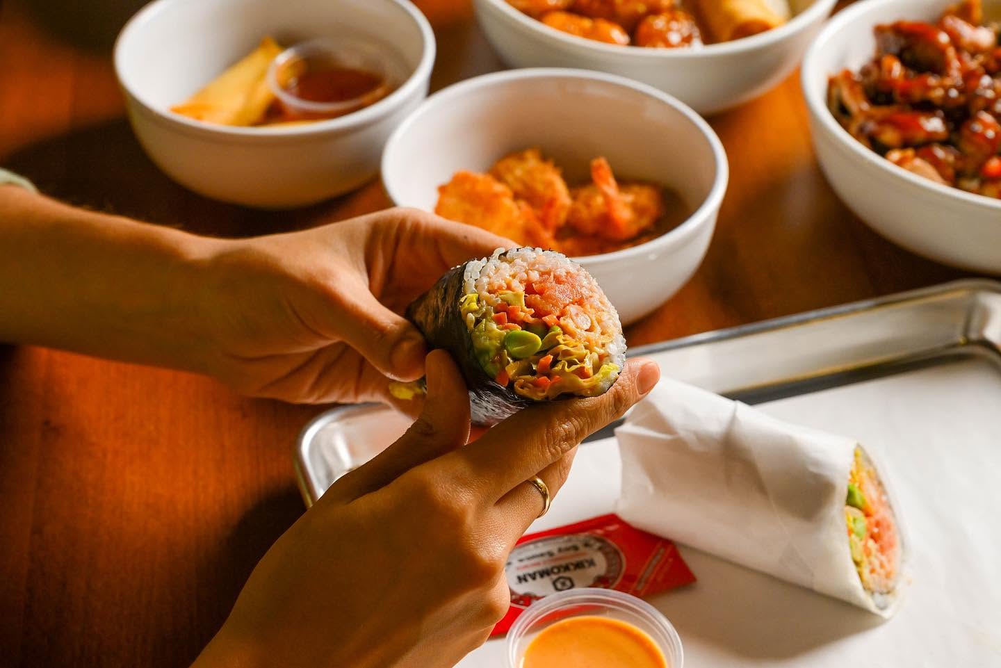 Handcrafted sushi burrito cut open showing layers of fresh salmon, avocado, edamame, and carrots at Nori in Omaha
