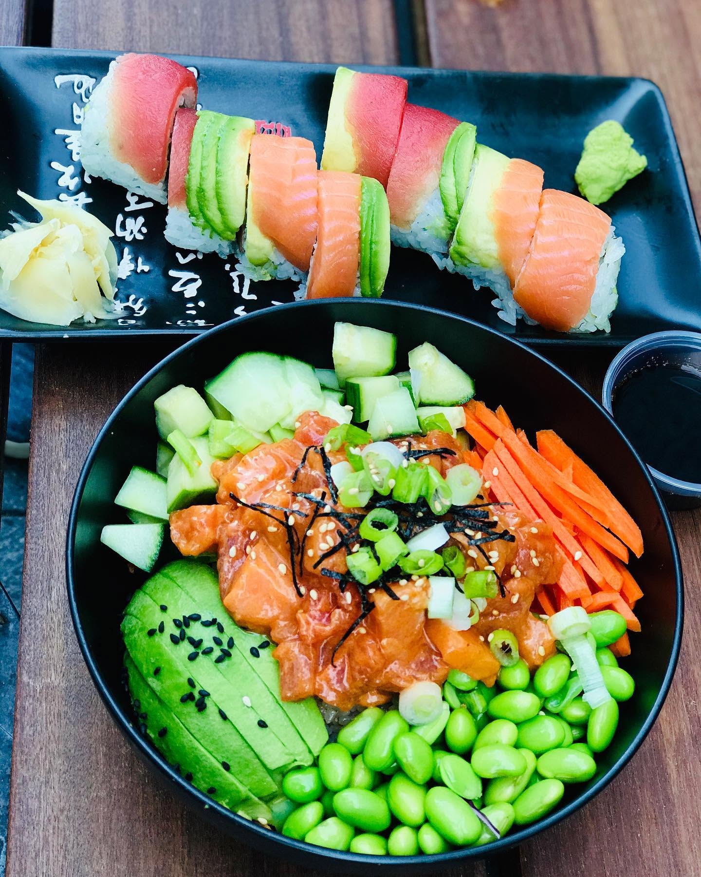 Fresh salmon poke bowl with sliced avocado, edamame, cucumber, and a fresh sushi roll at Nori in Omaha