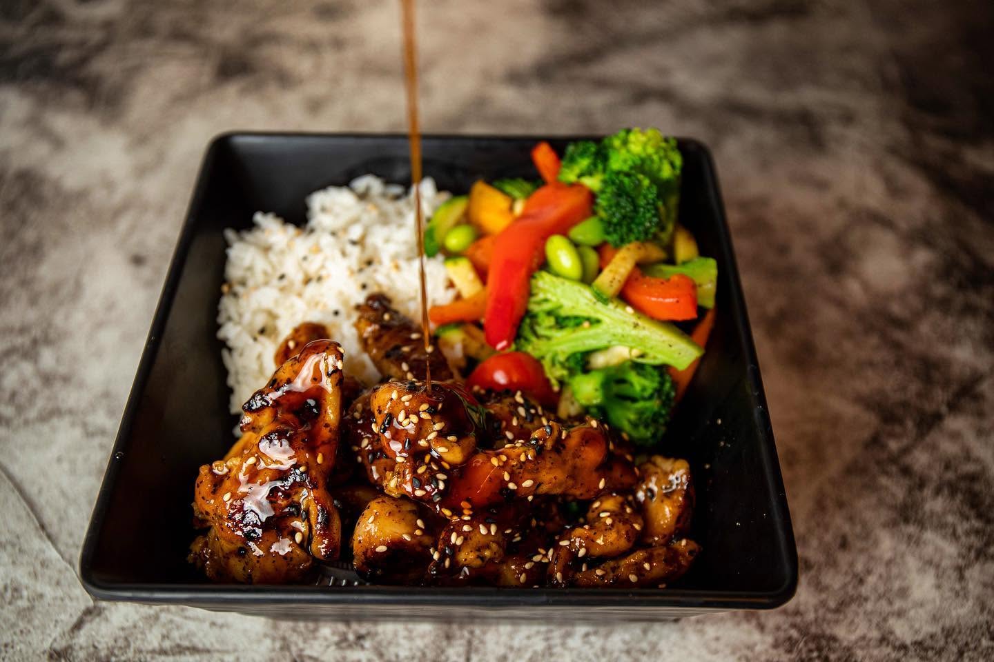 Savory teriyaki sauce drizzled over sesame glazed chicken with grilled vegetables and rice at Nori in Omaha