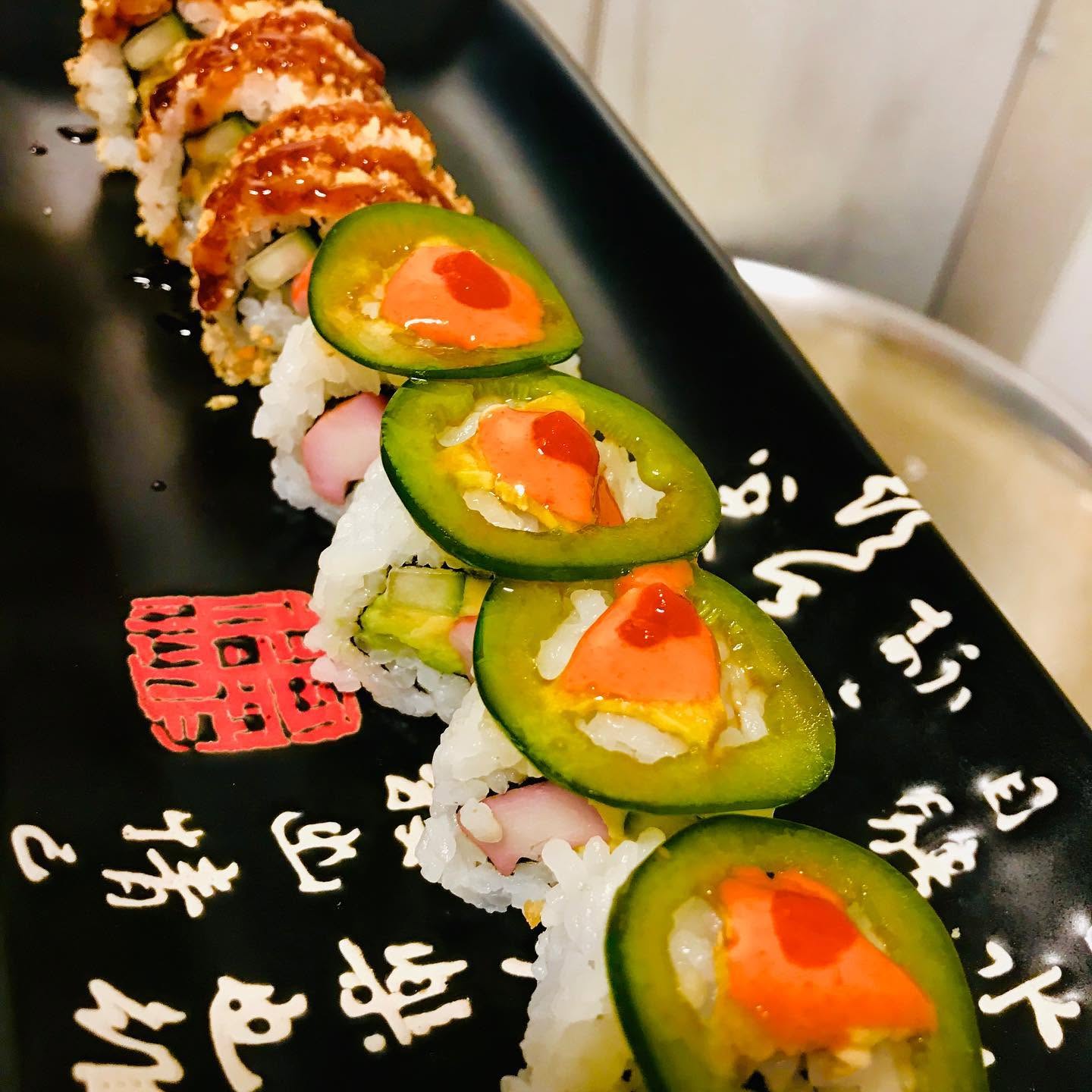 Specialty sushi rolls topped with fresh jalapeno slices and spicy sauce on a ceramic plate at Nori in Omaha