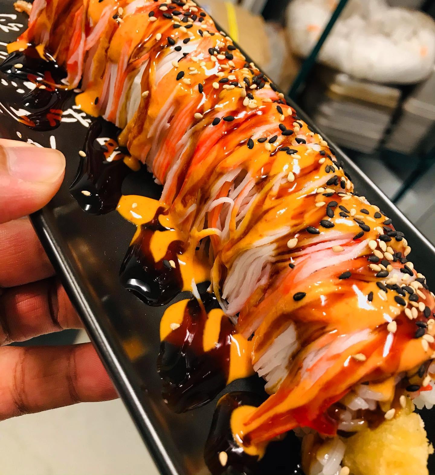 Loaded specialty sushi roll draped in shredded crab, spicy aioli, sweet glaze, and sesame seeds at Nori in Omaha