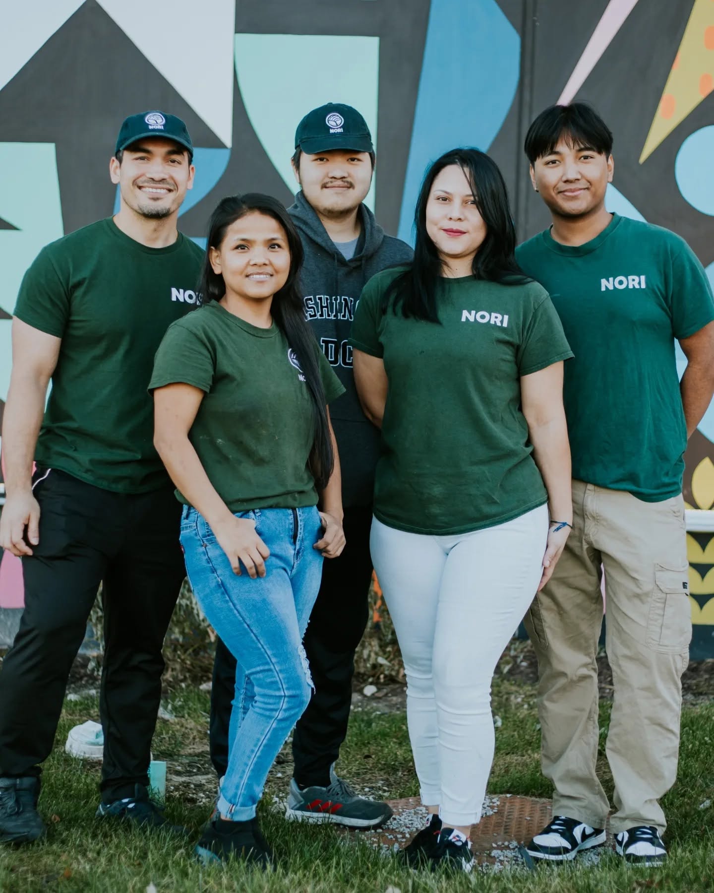 The Nori sushi restaurant team in Omaha smiling together in green Nori shirts