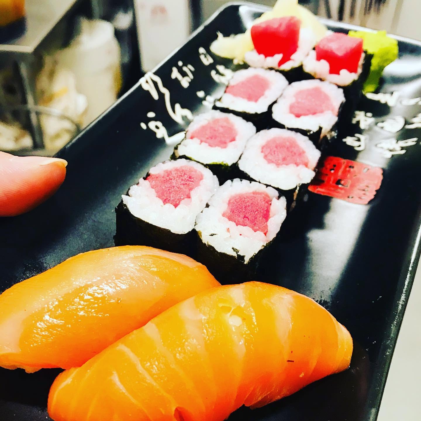 Fresh salmon nigiri and tuna maki sushi rolls on a black ceramic dish at Nori in Omaha