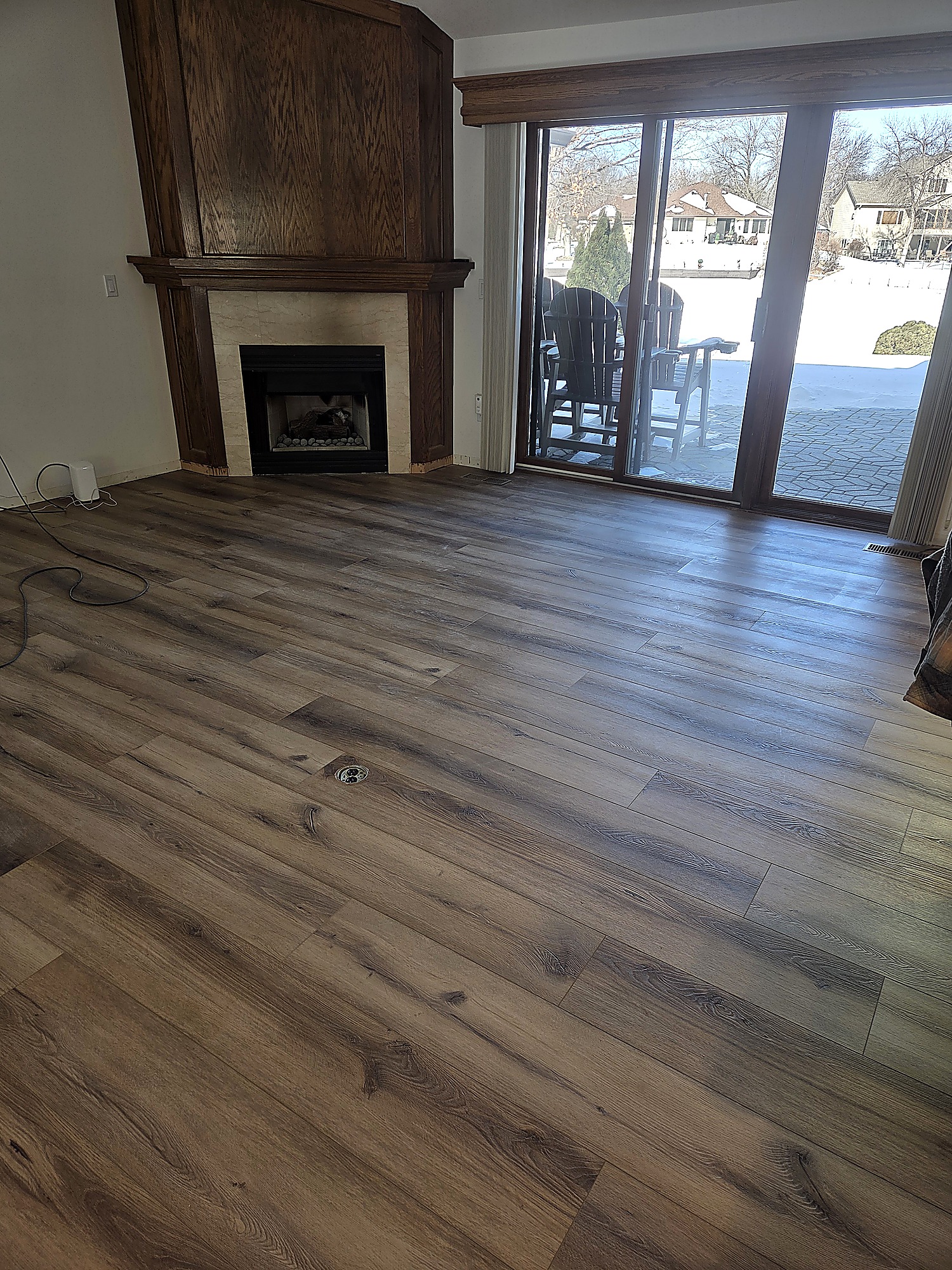 Wood-look plank flooring in a living room with a corner fireplace