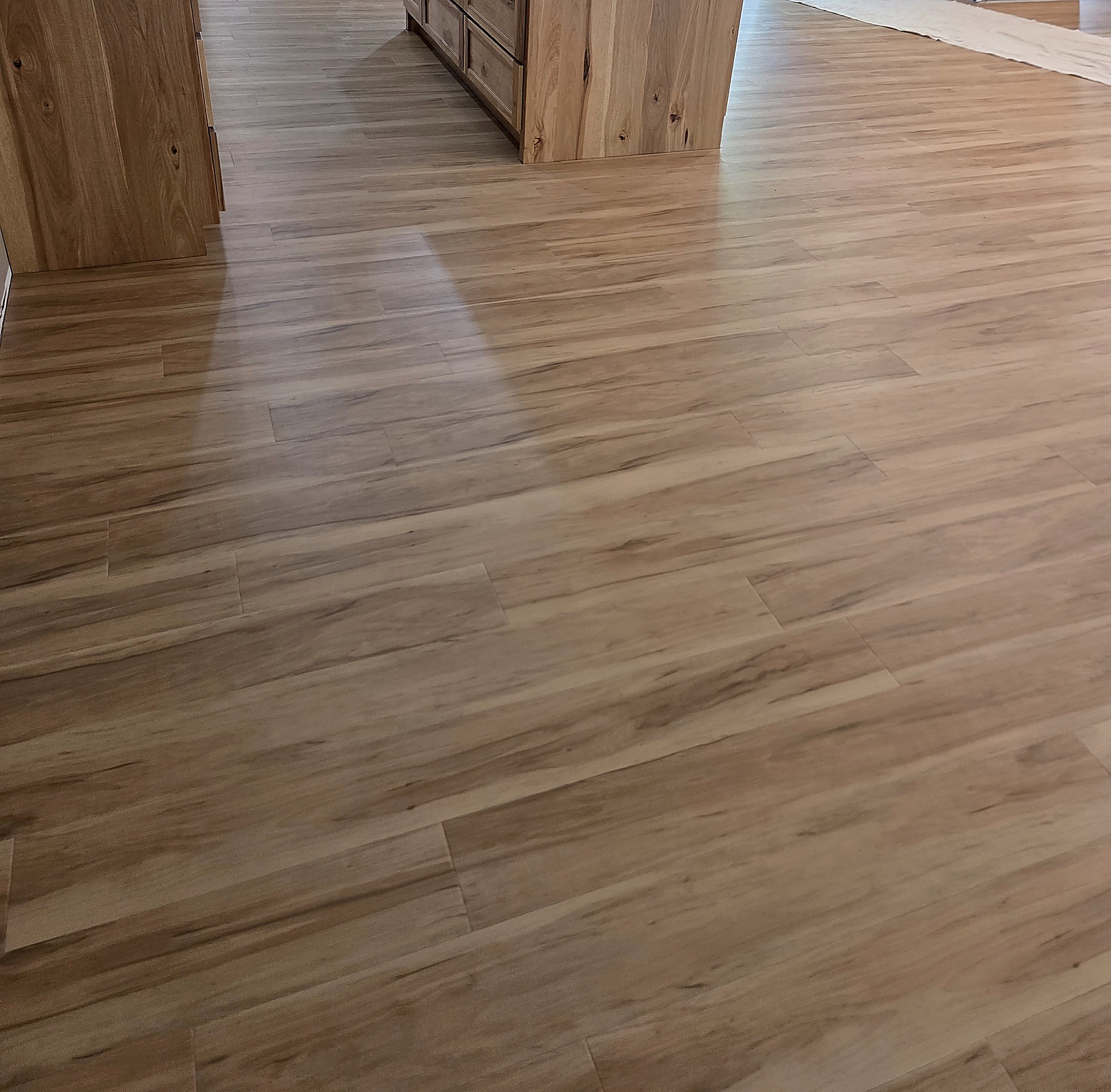 Warm wood-look plank flooring in a kitchen with a hickory island