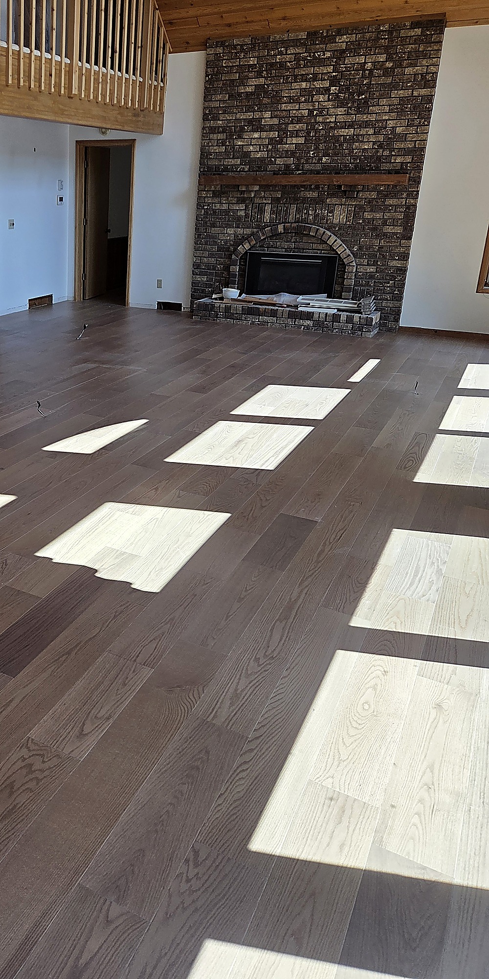 Dark wood plank flooring in a great room with a brick fireplace