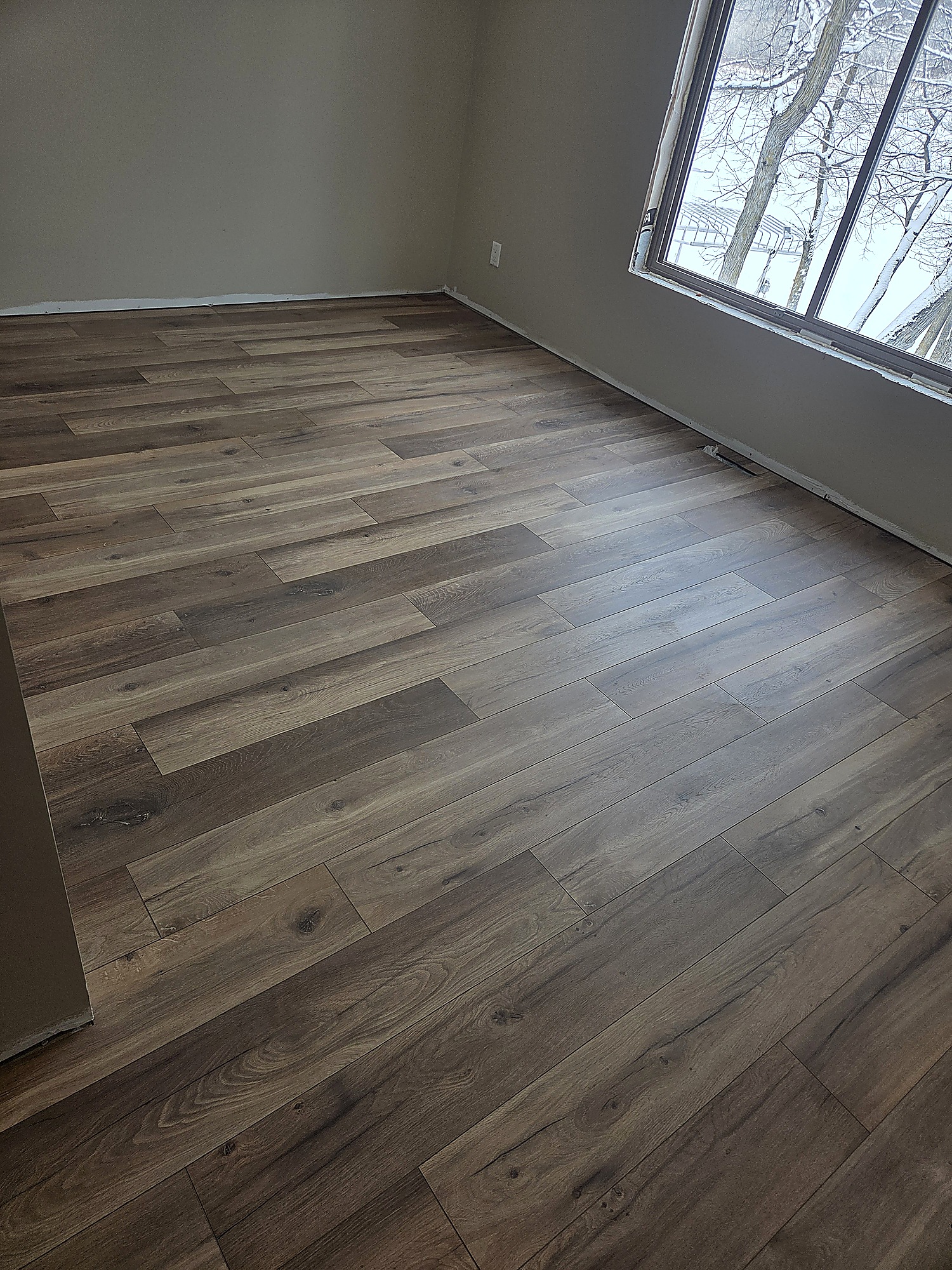 Wood-look plank flooring in a room with a snowy window view