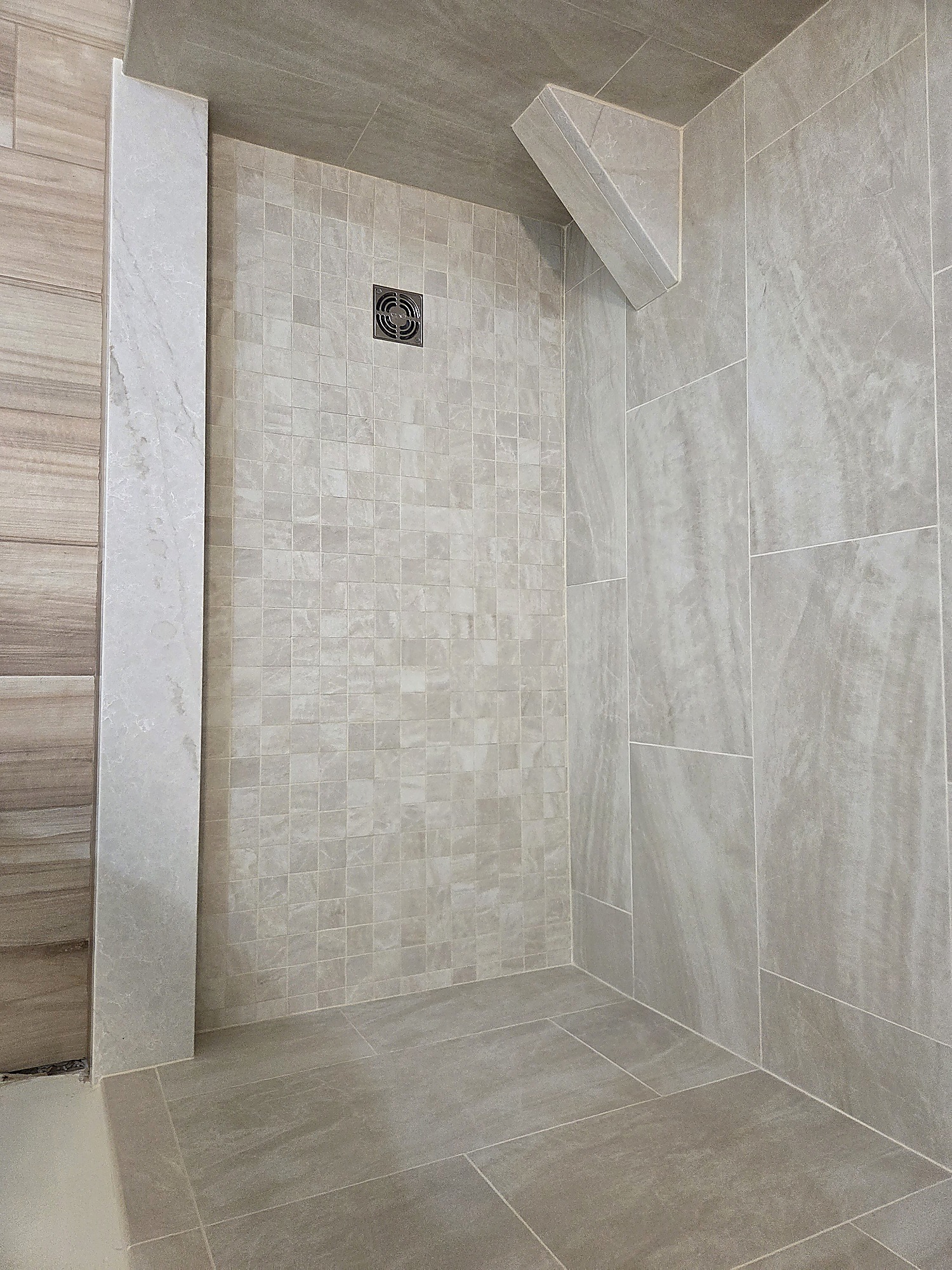 Close-up of mosaic shower floor tile and stone-look wall tile