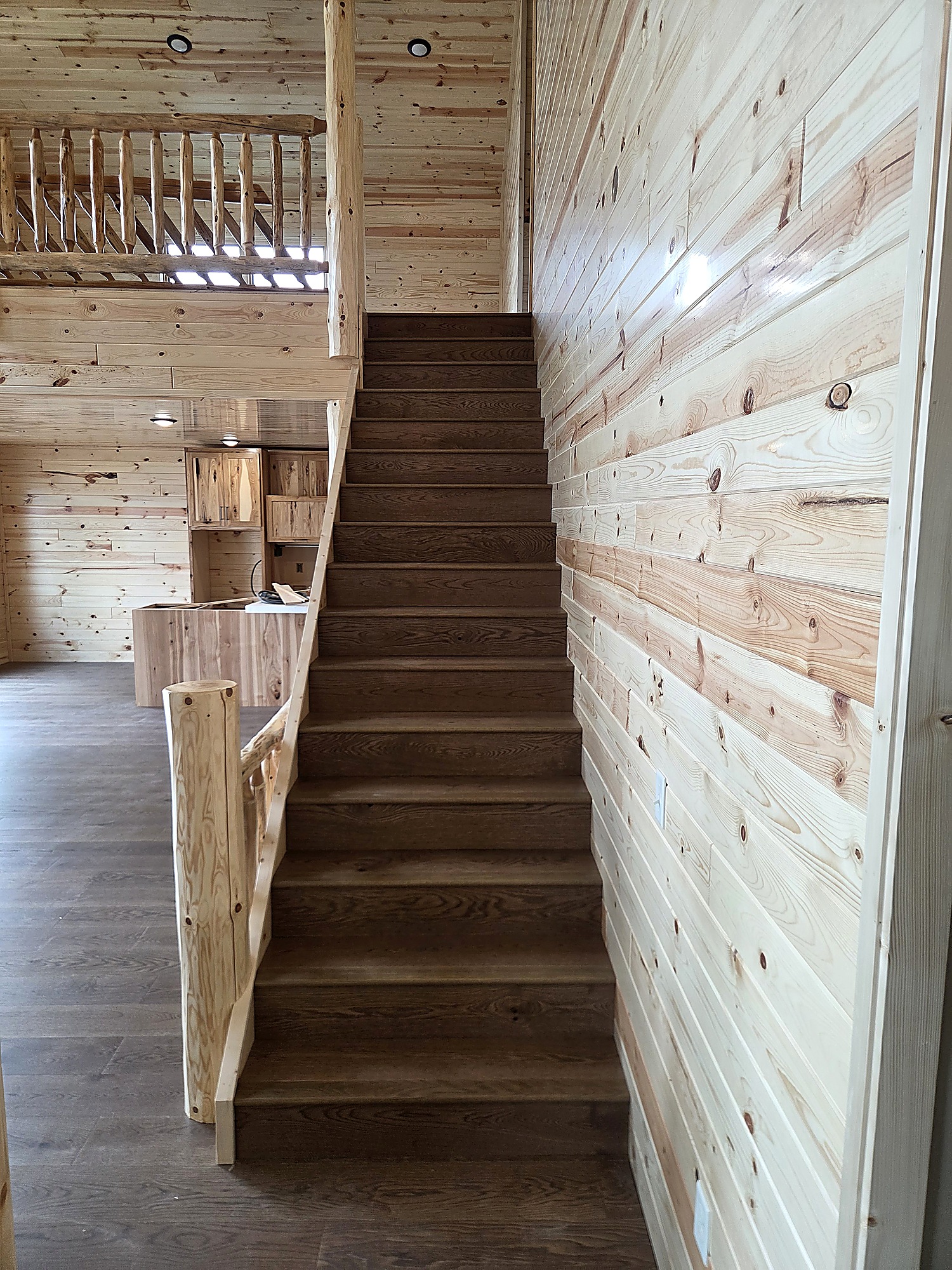 Dark oak staircase with a log railing in a lake cabin