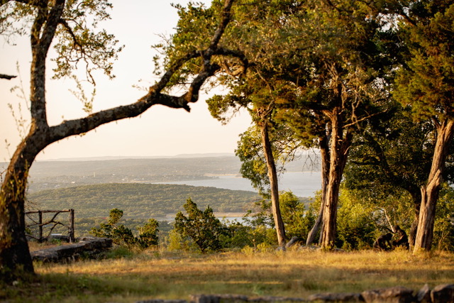 Scenic overlook view from the hillside through tall trees across Canyon Lake and the rolling Texas Hill Country