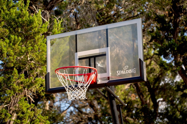 Spalding basketball hoop among mature cedar and oak trees at The Point CLTX