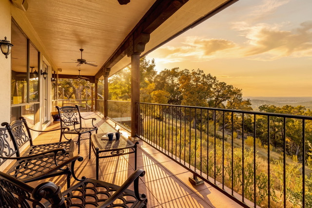 Warm covered porch and veranda with wrought-iron lounge chairs overlooking golden hour Hill Country vistas at The Point CLTX