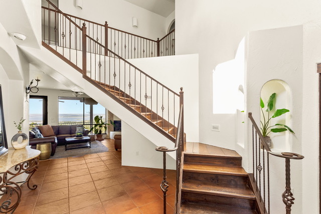 Spacious interior foyer with architectural wooden staircase, terracotta tile, and view through to Canyon Lake vistas